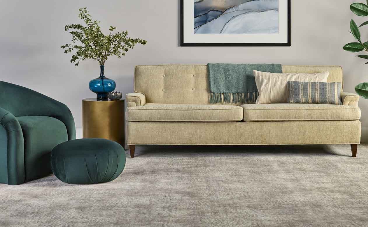 Living room with velvet green and cream furniture and gray patterned carpet.